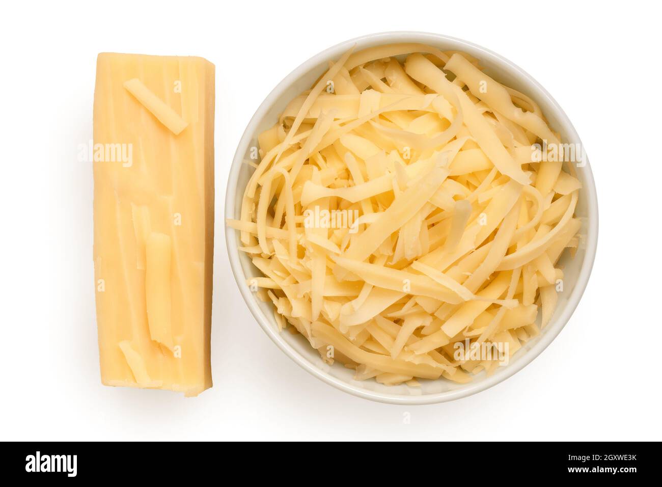 Grated cheese in a white ceramic bowl next to a block of cheese. Top view. Stock Photo