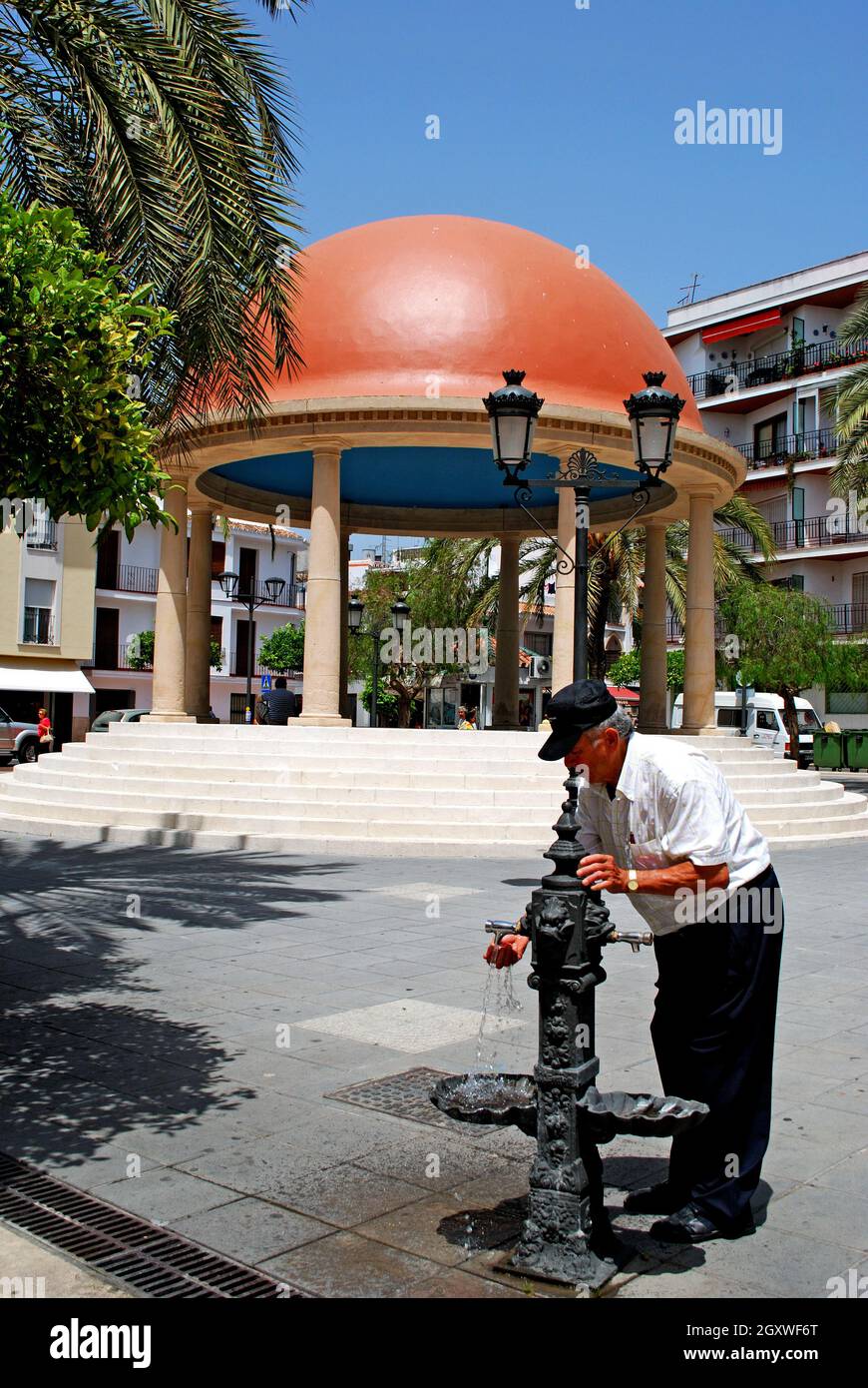 Man taking water from drinking fountain in the Plaza Antonia Guerrero, Estepona, Malaga Province