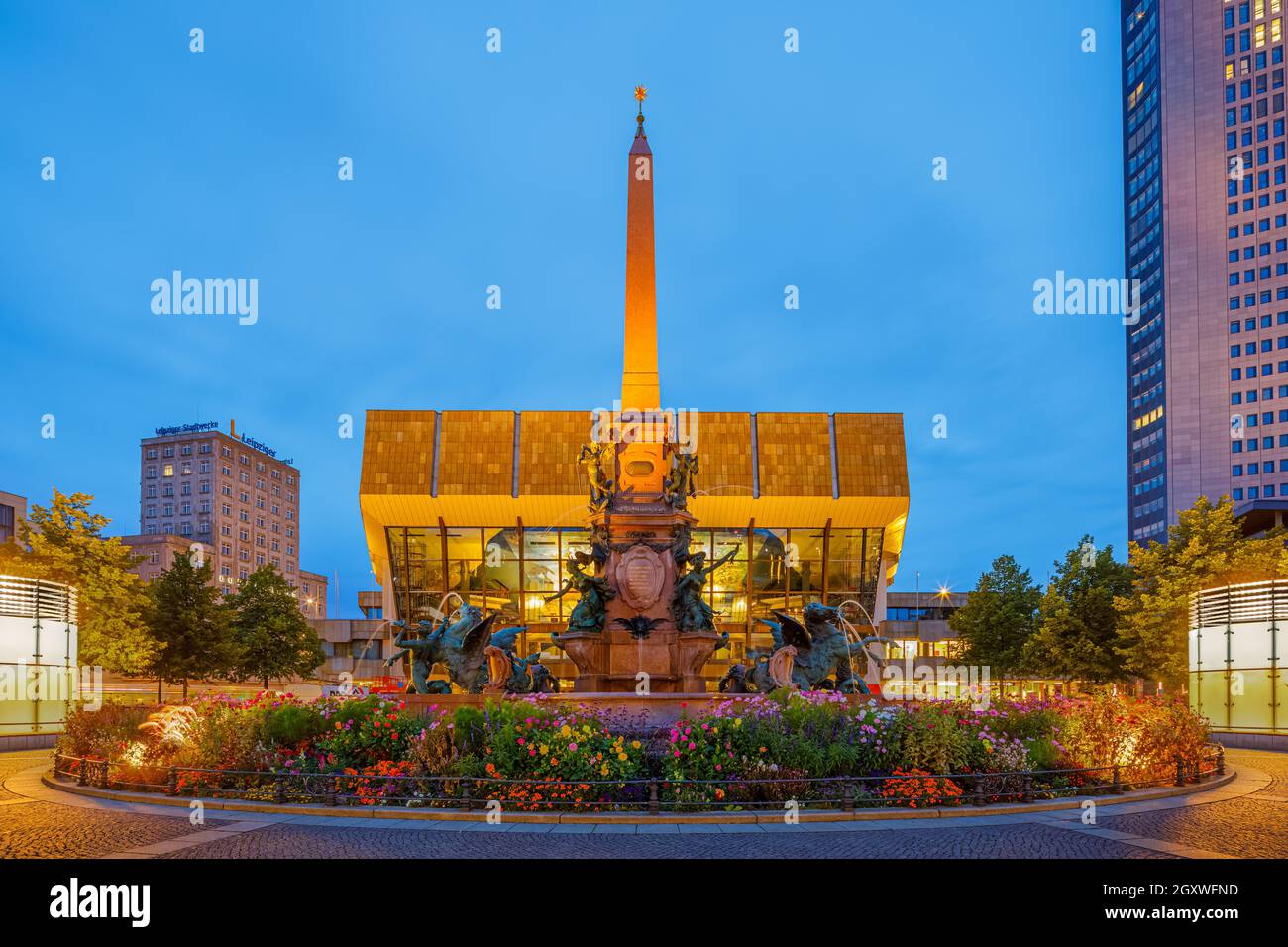 Downtown in Leipzig in evening blue hour light with the The Mende Fountain, located at Augustusplatz in front of the Gewandhaus (Concert Hall). It is Stock Photo
