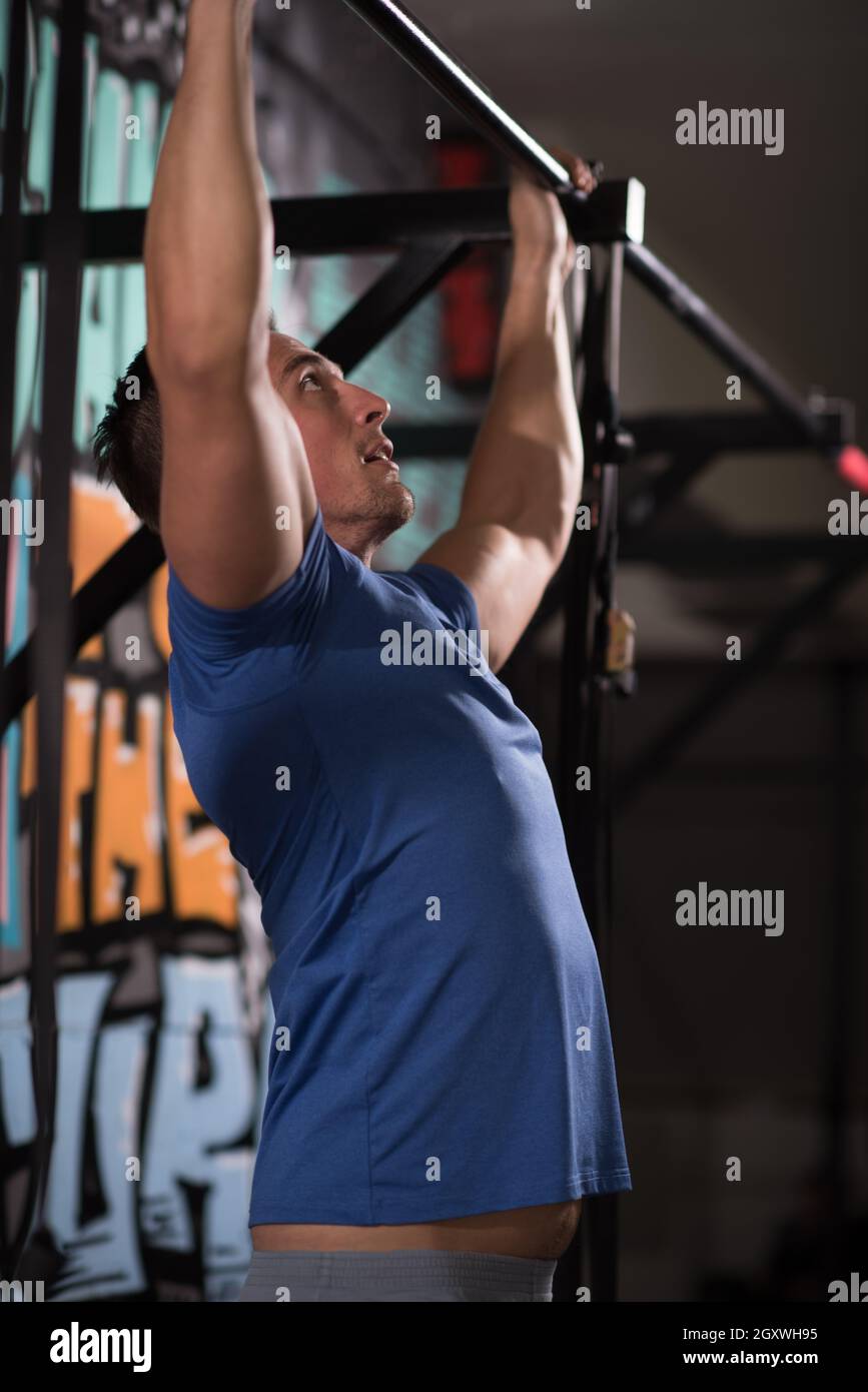 strong young man doing pull ups on a bar in a gym Stock Photo - Alamy