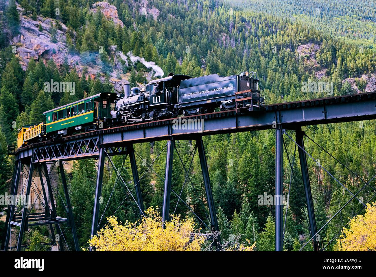 Old locomotive train going over bridge in the mountains Stock Photo