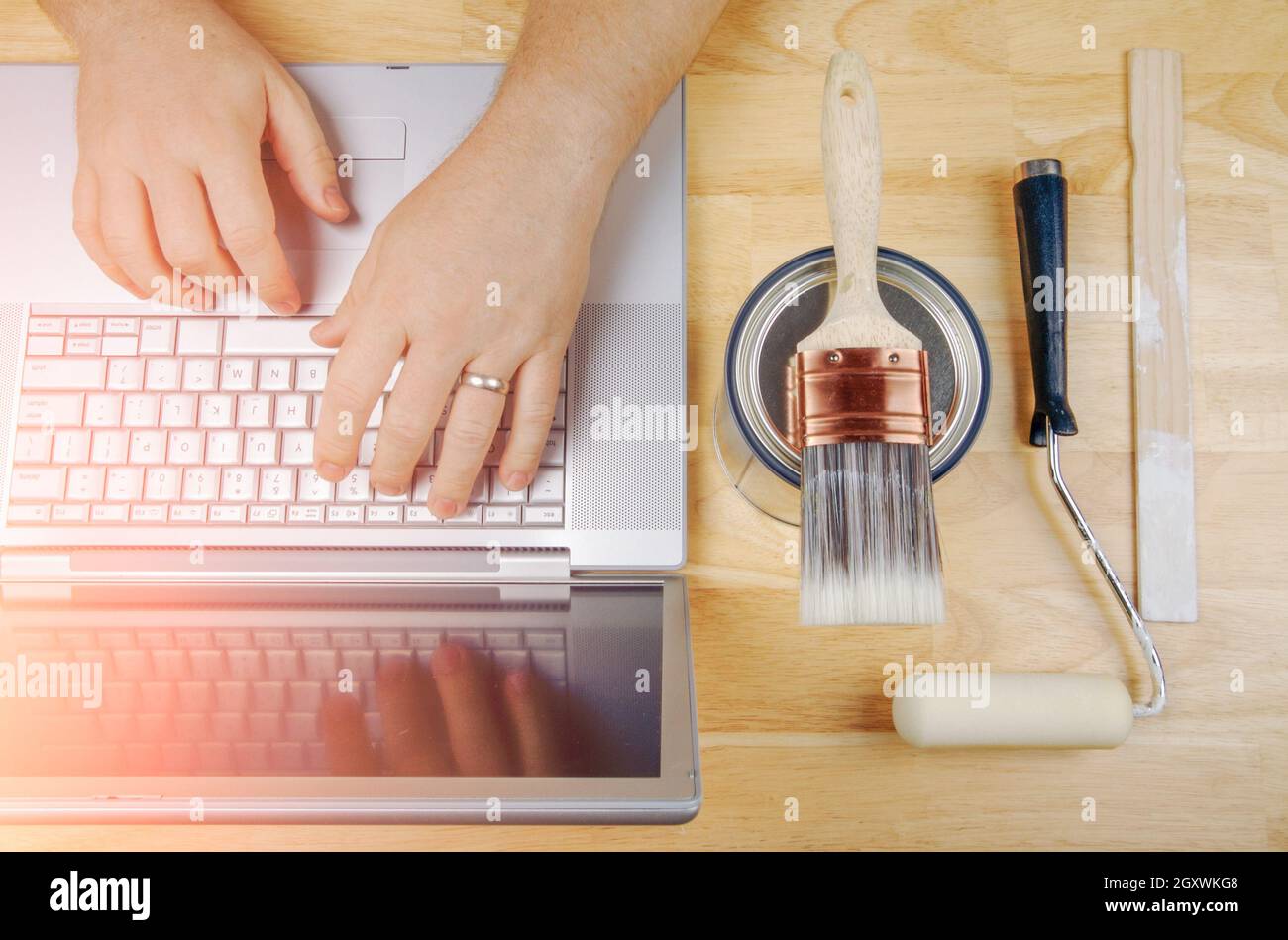 Paint Tools Next to Handyman Using Laptop Overhead. Stock Photo