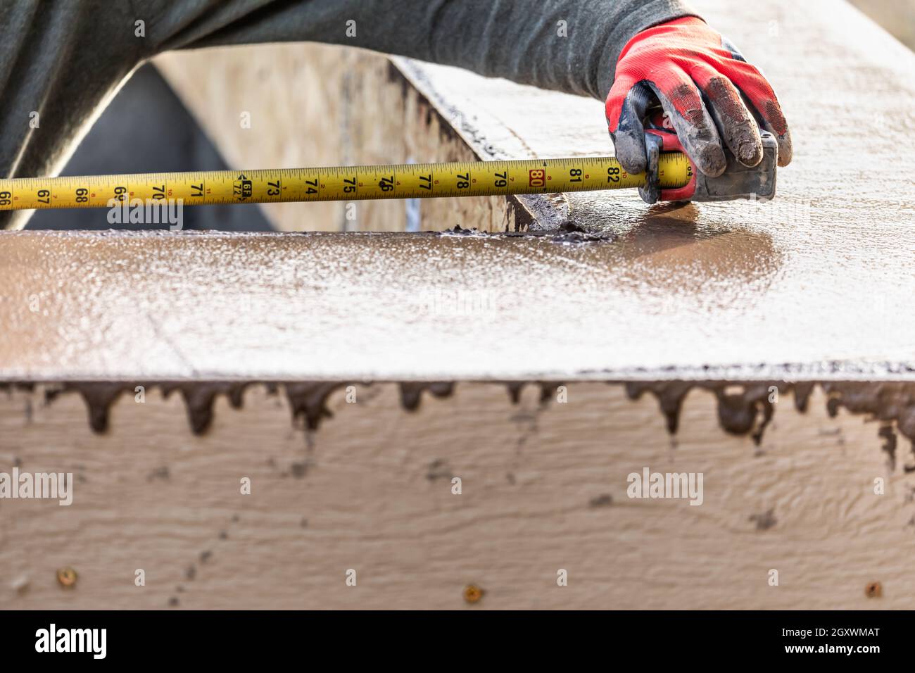 Cement Construction Worker Using Measuring Tape While Forming Pool Coping. Stock Photo