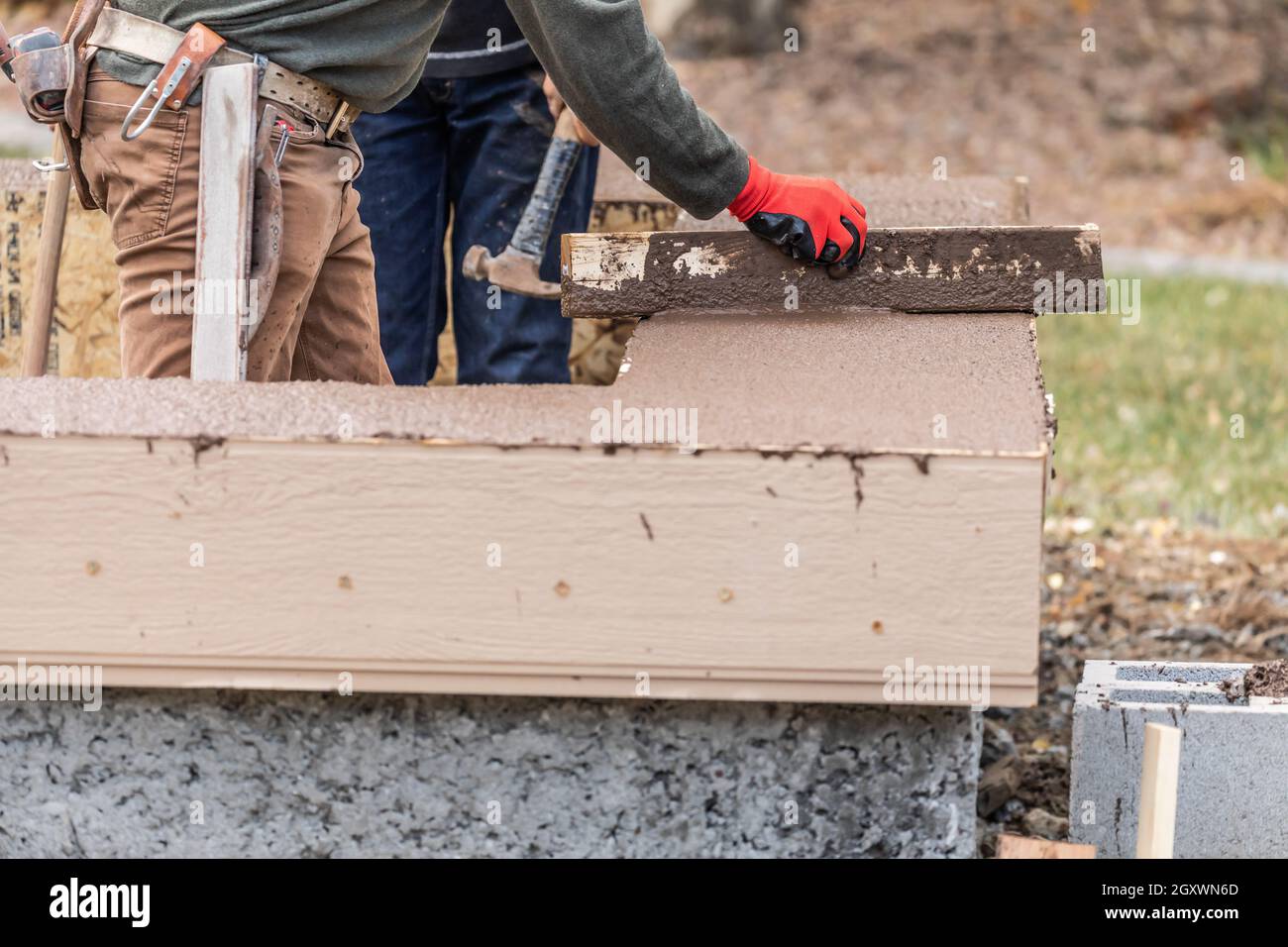 Construction Worker Leveling Wet Cement Into Wood Framing Stock Photo