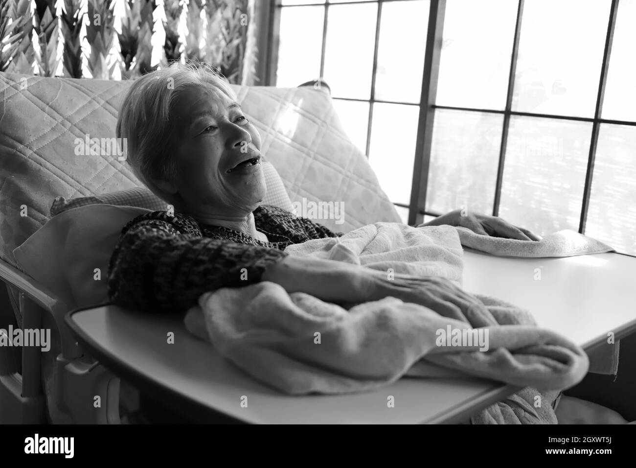 A smiling senior woman with dementia lying down on the nursing bed