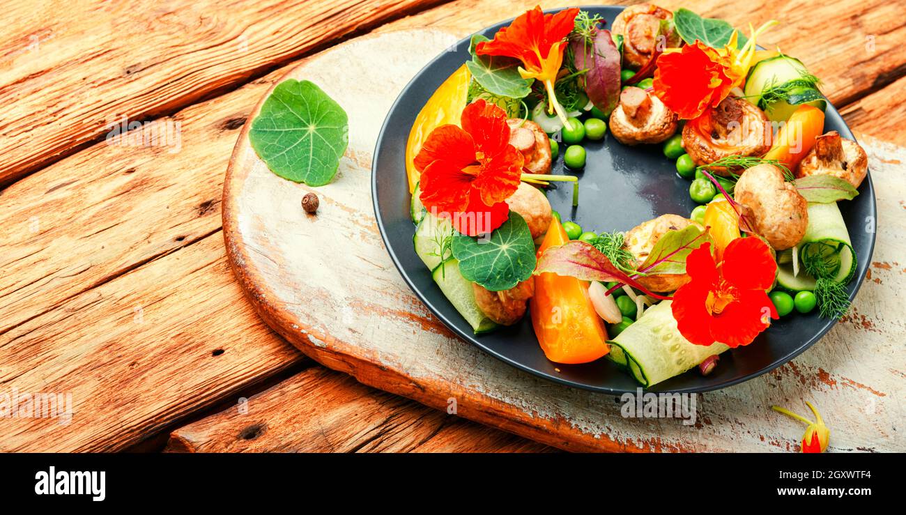 Salad with stewed mushrooms, cucumber,tomato and nasturtium. Stock Photo