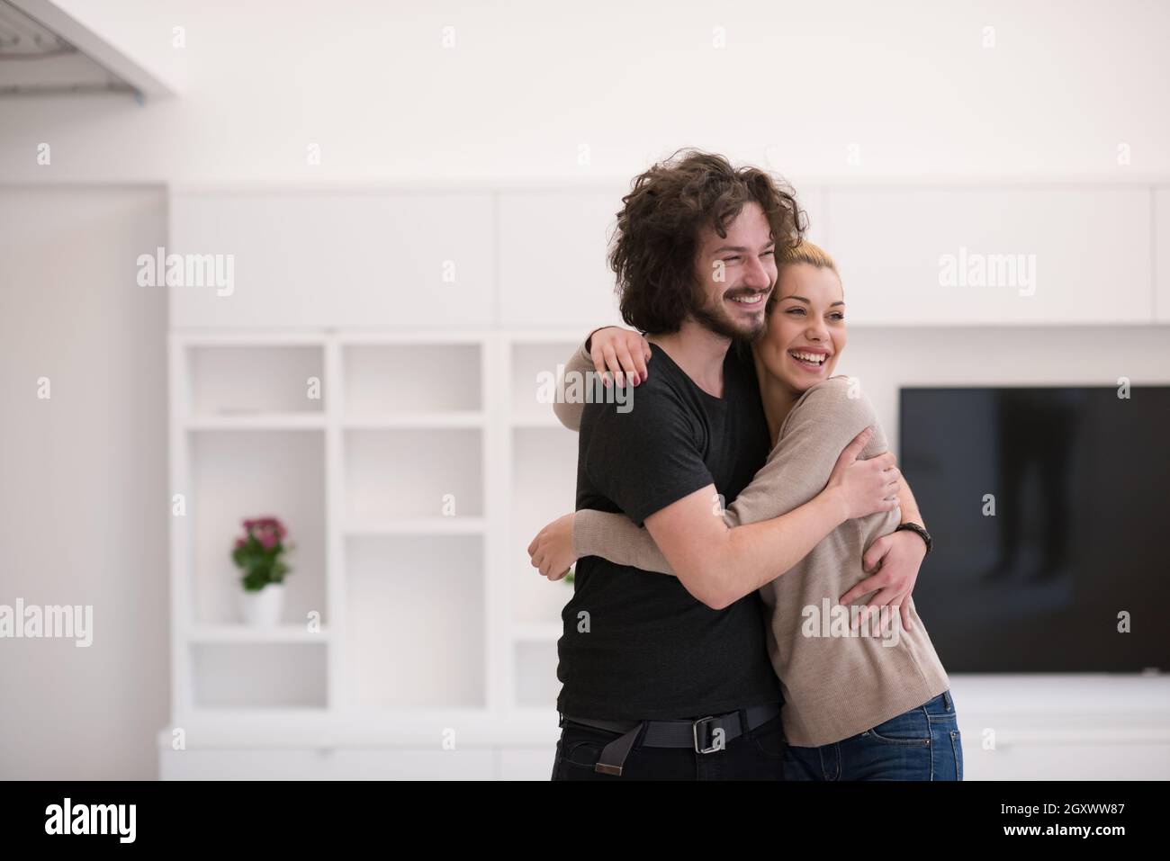 Portrait of a happy young beautiful couple hugging in their new home ...