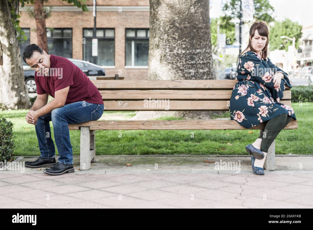 Unhappy Mixed Race Couple Sitting Facing Away From Each Other on Park