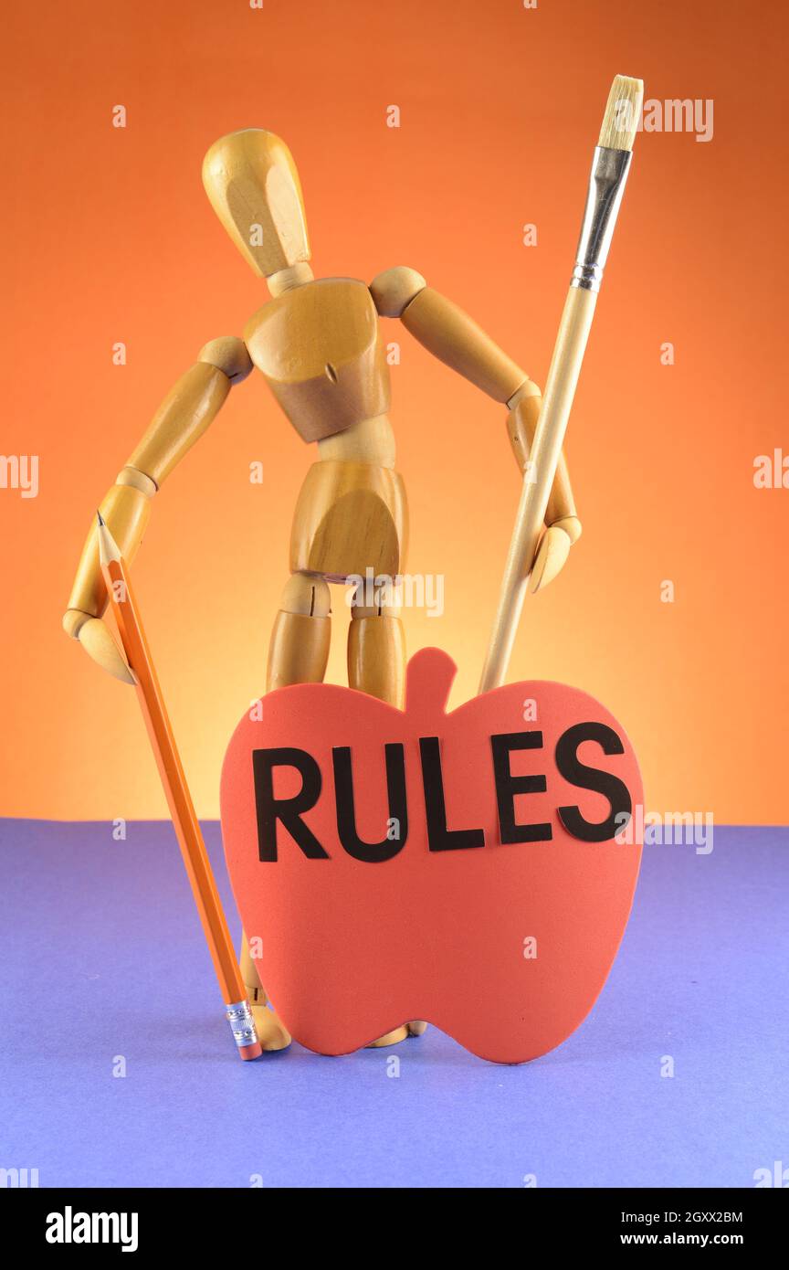 An Artist wooden Dummy Mannequin showcases the importance of rules in the fine art world while holding a pencil and a paintbrush. Stock Photo