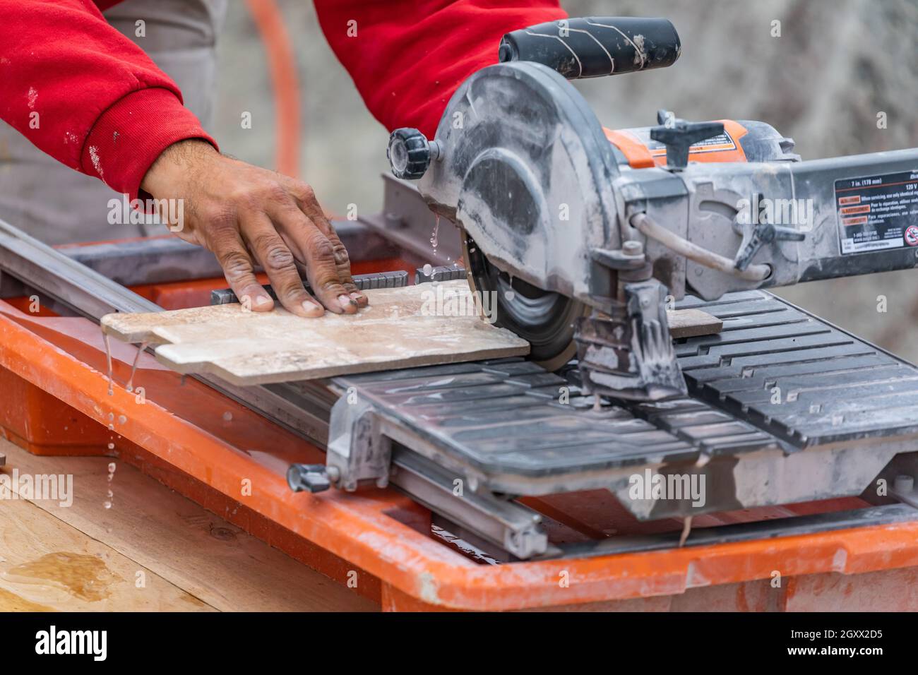 Worker Using Wet Tile Saw to Cut Wall Tile At Construction Site. Stock Photo