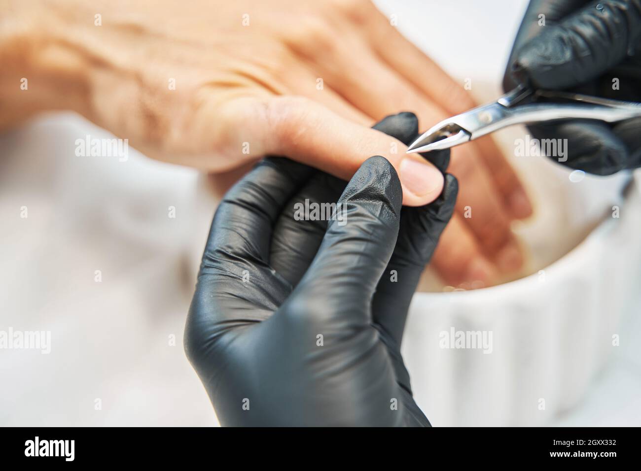 Manicurist nipping away skin from nail with cuticle cutter Stock Photo