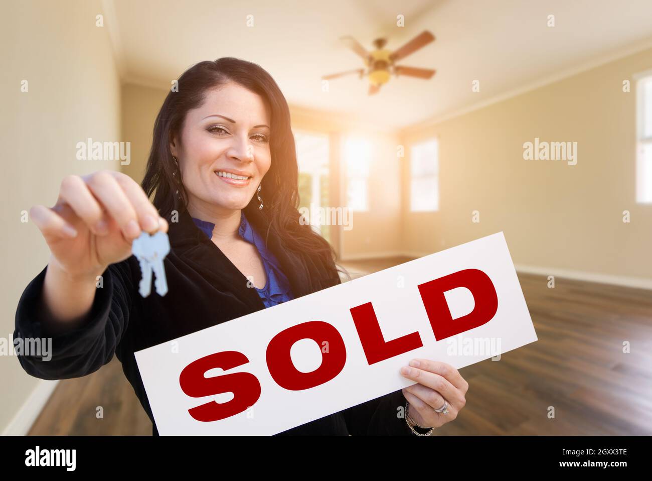 Hispanic Woman With House Keys and Sold Real Estate Sign In Empty Room ...
