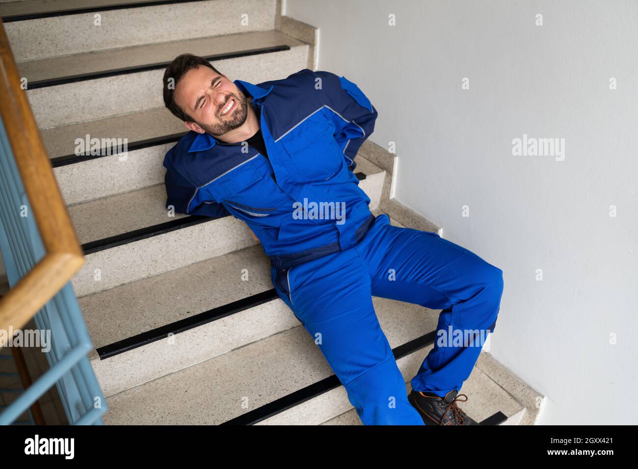 Worker Man Lying On Staircase After Slip And Fall Accident Stock Photo