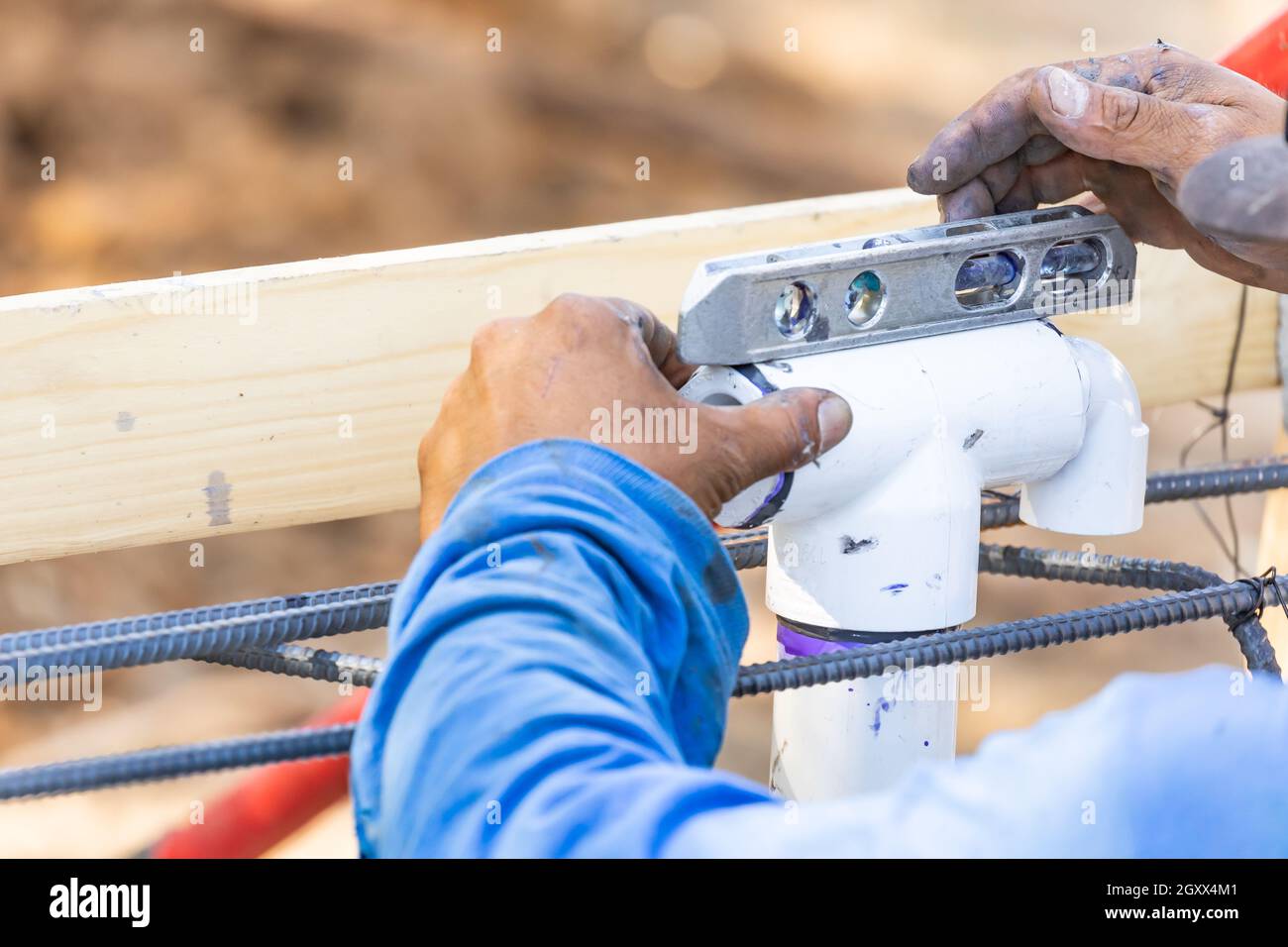 Plumber Using Level While Installing PVC Pipe At Construction Site