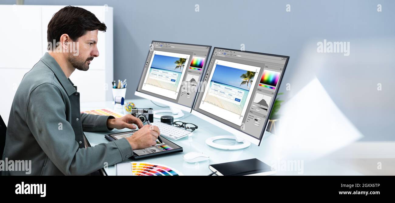 Designer And Photographer Using Multiple Computer Screens Stock Photo