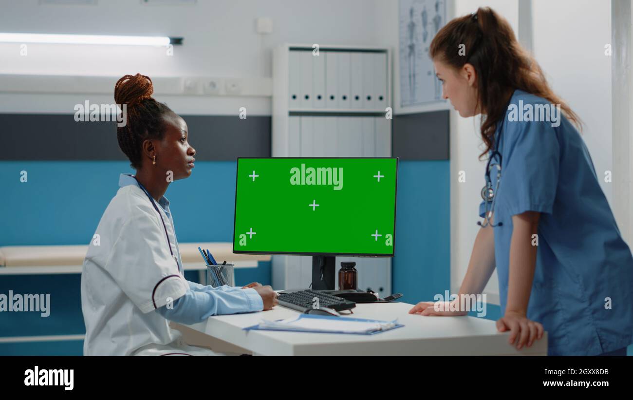 Doctor and nurse working with horizontal green screen on computer in ...