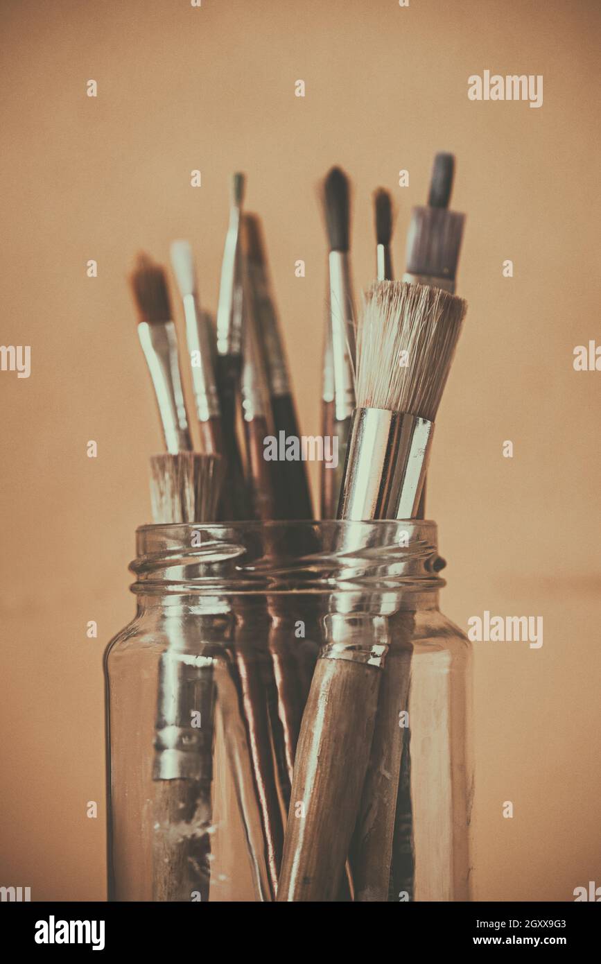 Assorted paintbrushes in a glass jar Stock Photo