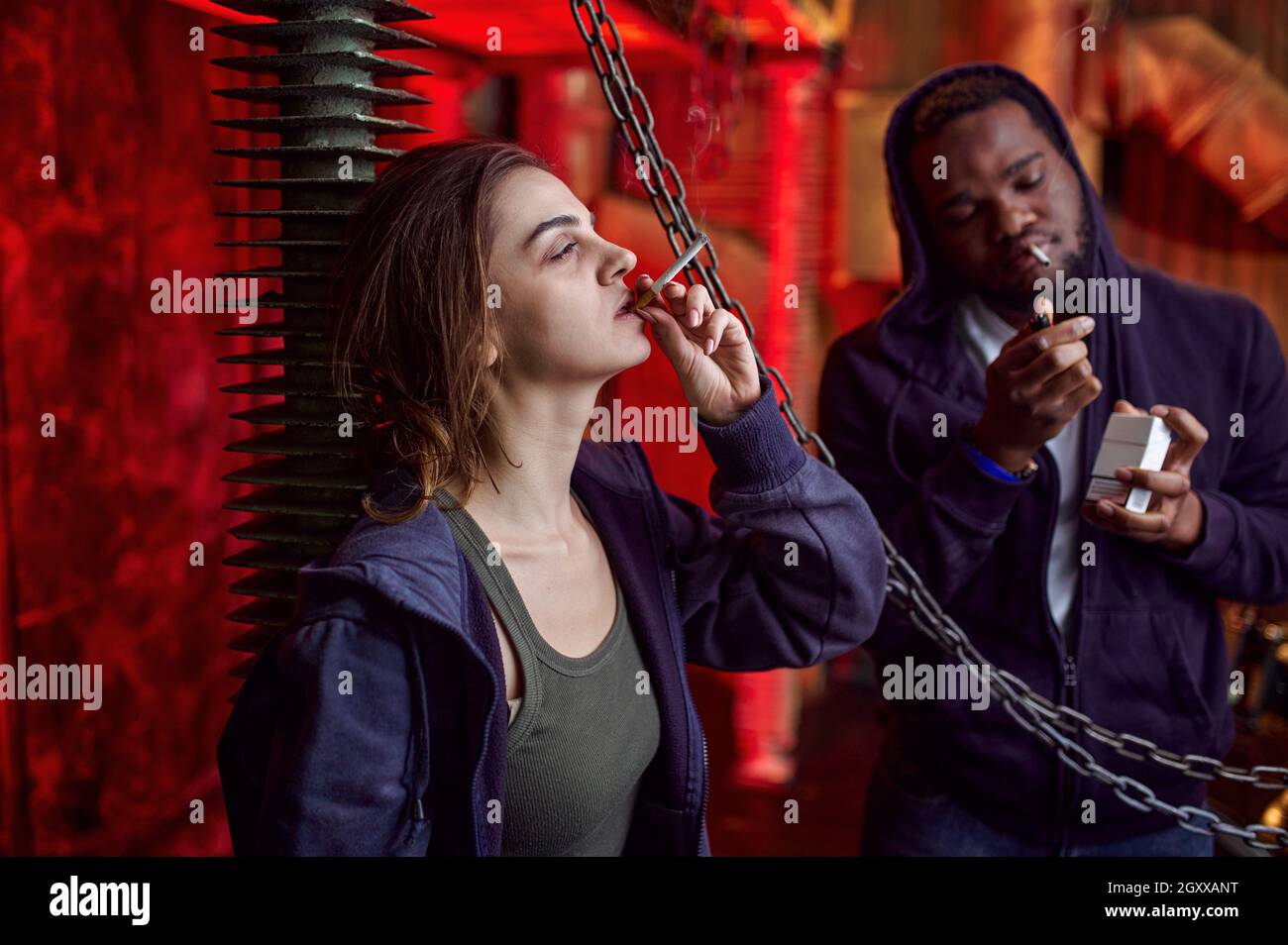 Drug addict man and woman smokes a cigarette while high in shebang. Narcotic addiction problem, eternal depression of junky people Stock Photo