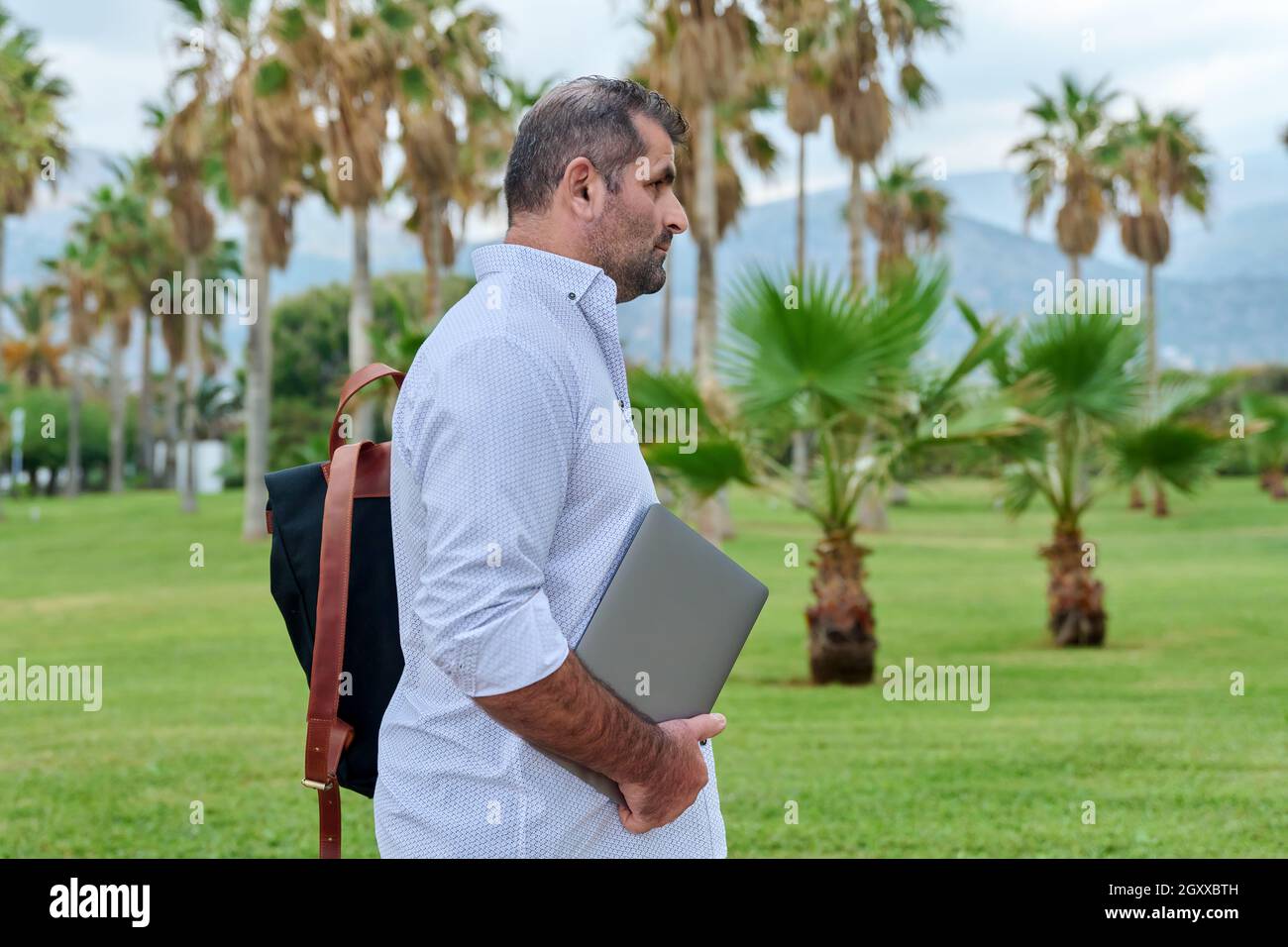 Portrait of serious confident mature man with laptop outdoors Stock Photo