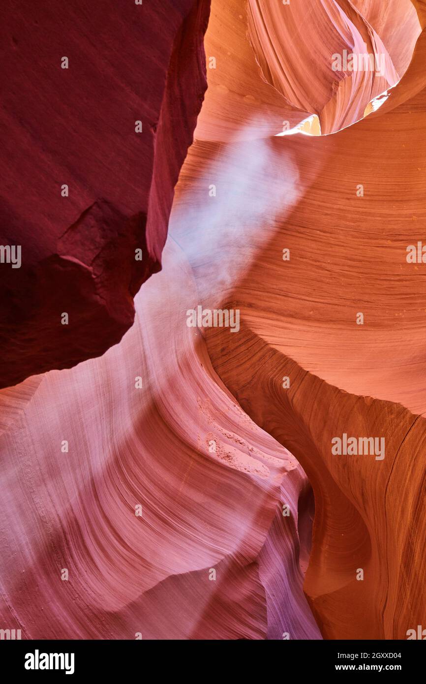 Light filters in from above and illuminates dust in an orange canyon Stock Photo