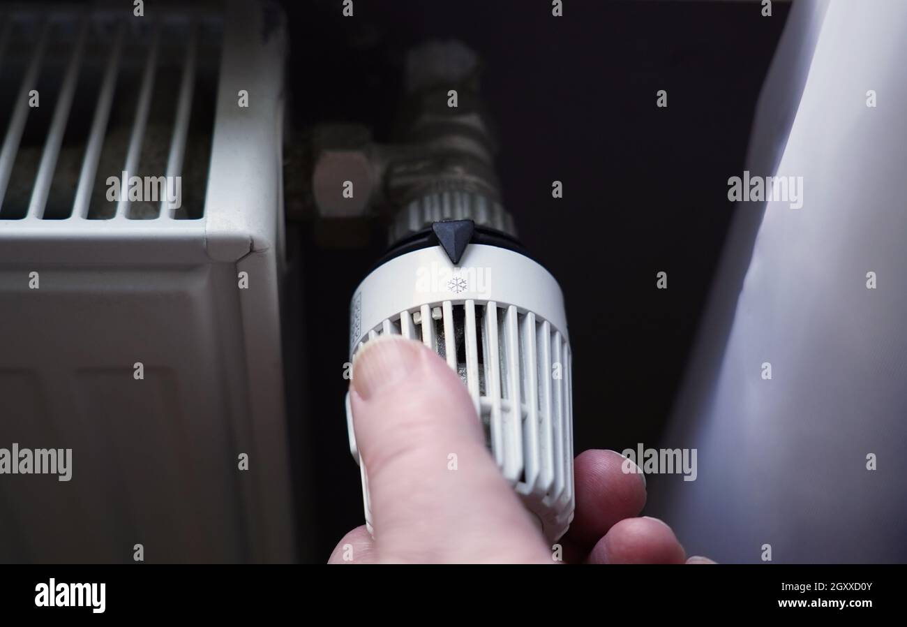 turning off thermostat on radiator to save energy due to increasing heating costs Stock Photo