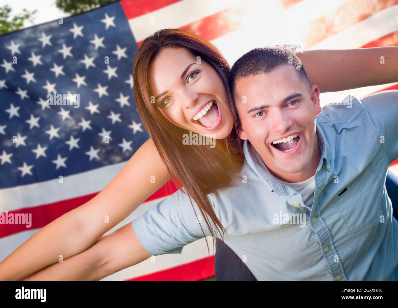 Military Couple Piggy Riding In Front of American Flag Stock Photo