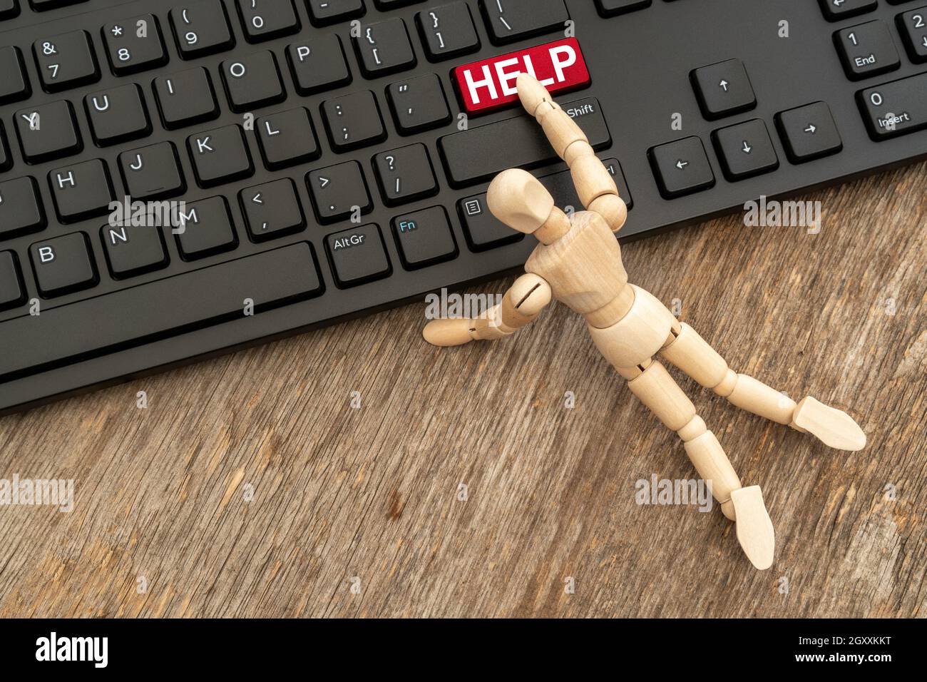 Online HELP button. Wooden dummy pressing HELP button on a computer keyboard. Stock Photo
