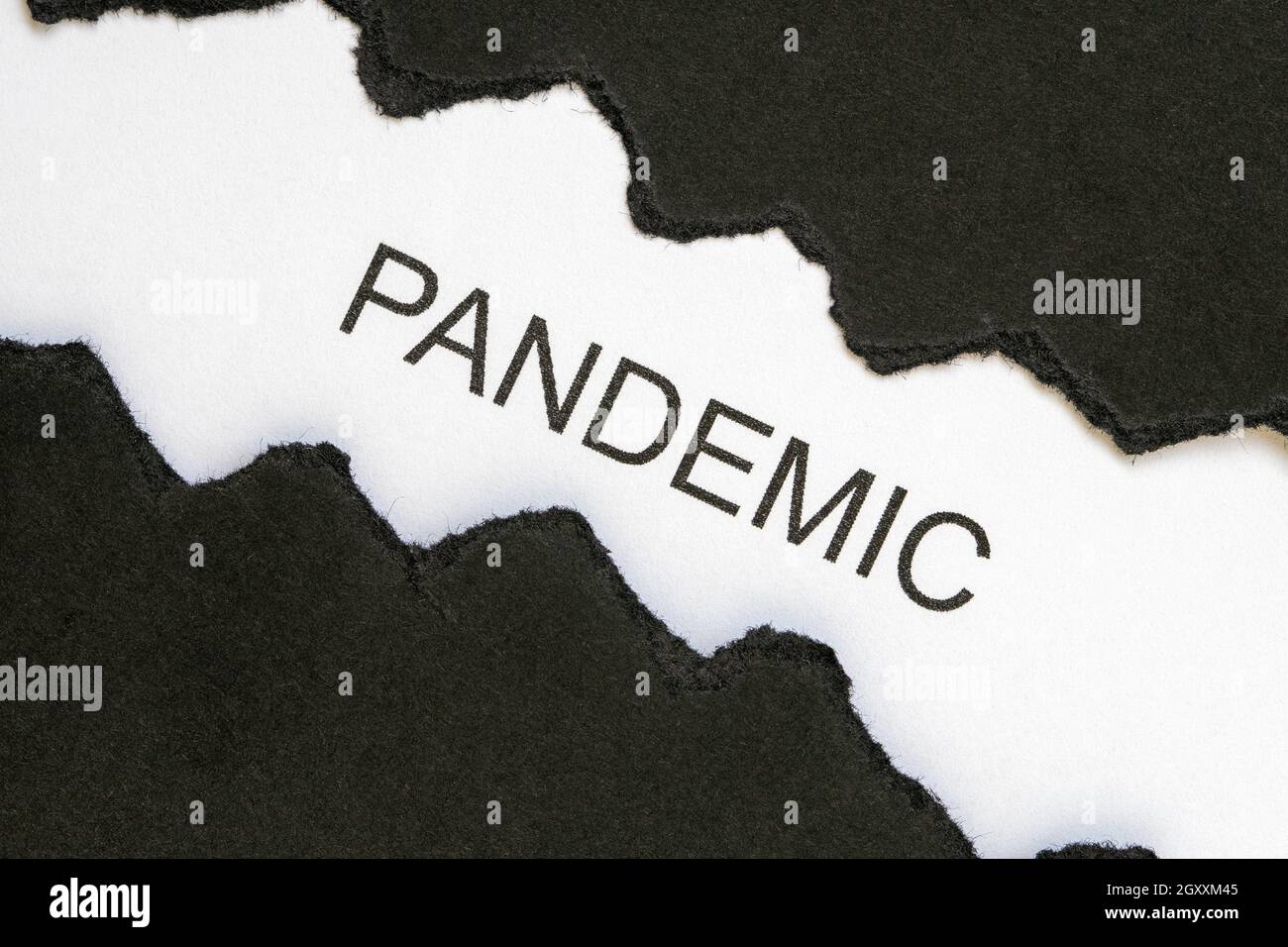 Top view of black torn paper and the word PANDEMIC on a white ...