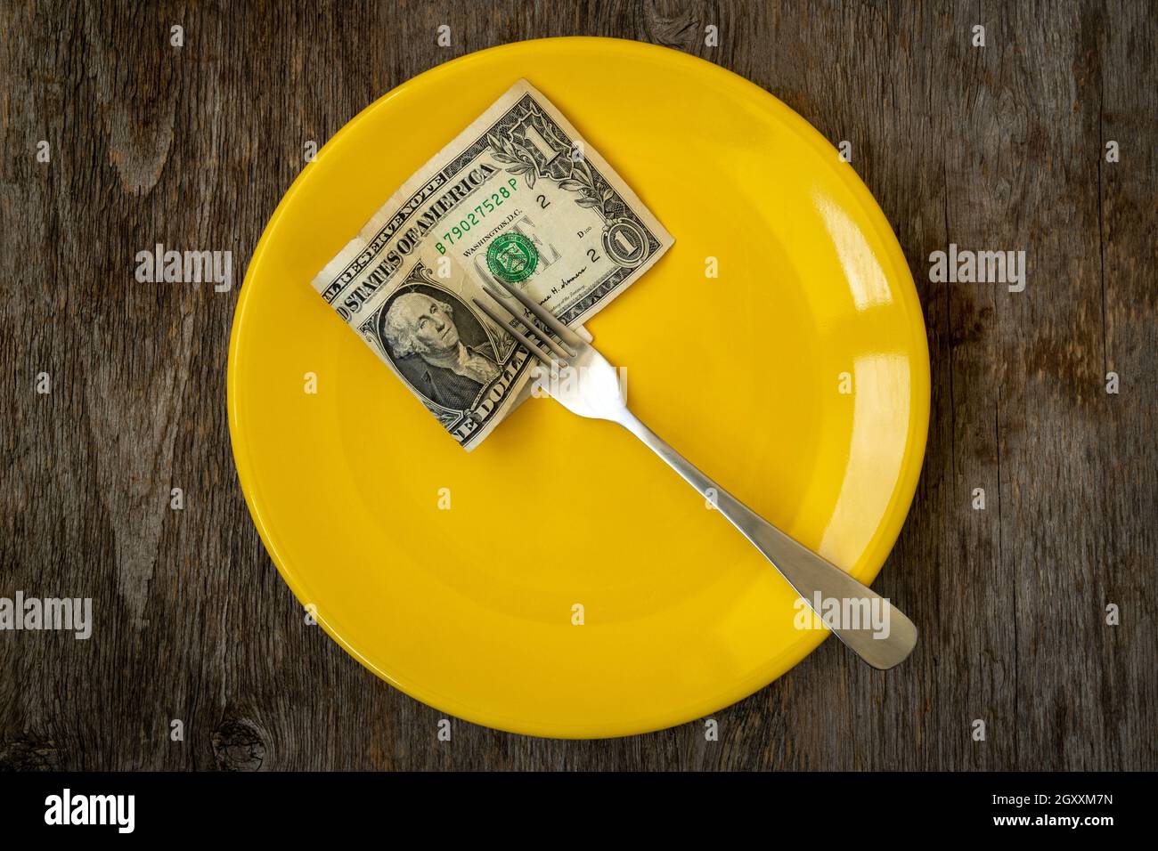 Economic crisis. One paper dollar with a fork  on a yellow plate. Dividing the budget. Concept of the global financial crisis. Lack of money for food. Stock Photo