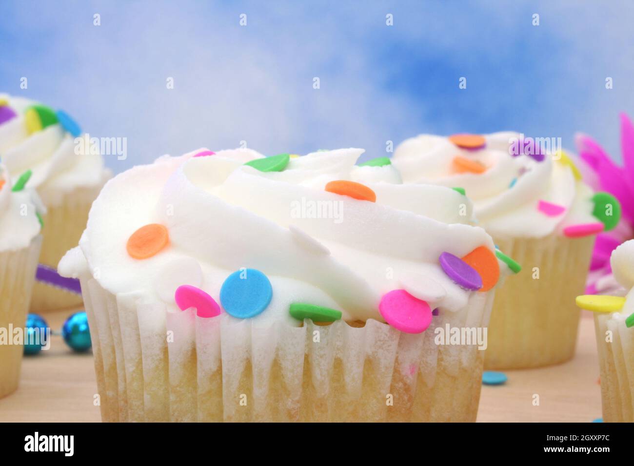 Cupcakes with brightly colored sprinkles on blue background Stock Photo