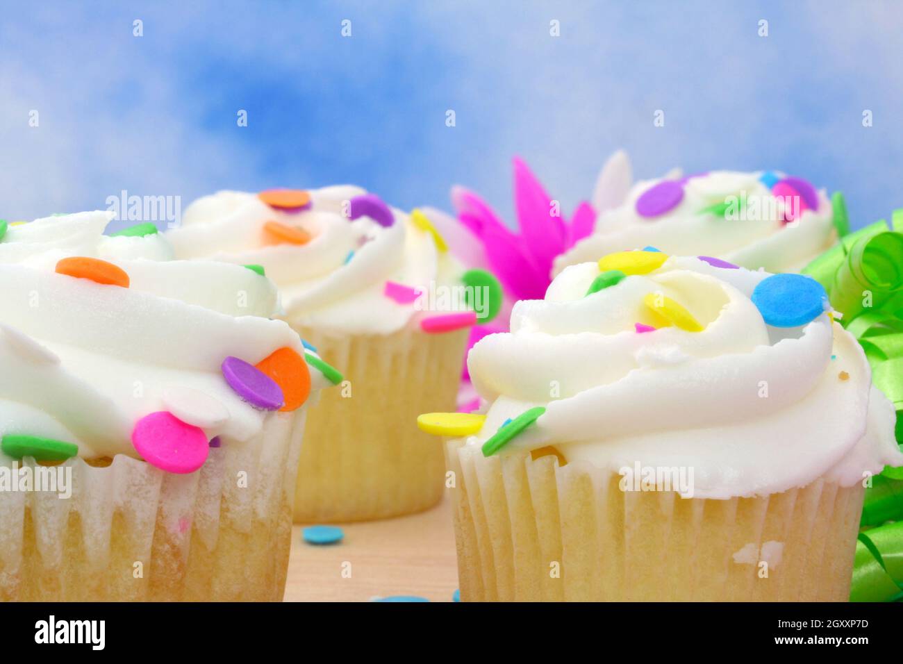 Cupcakes with brightly colored sprinkles on blue background Stock Photo