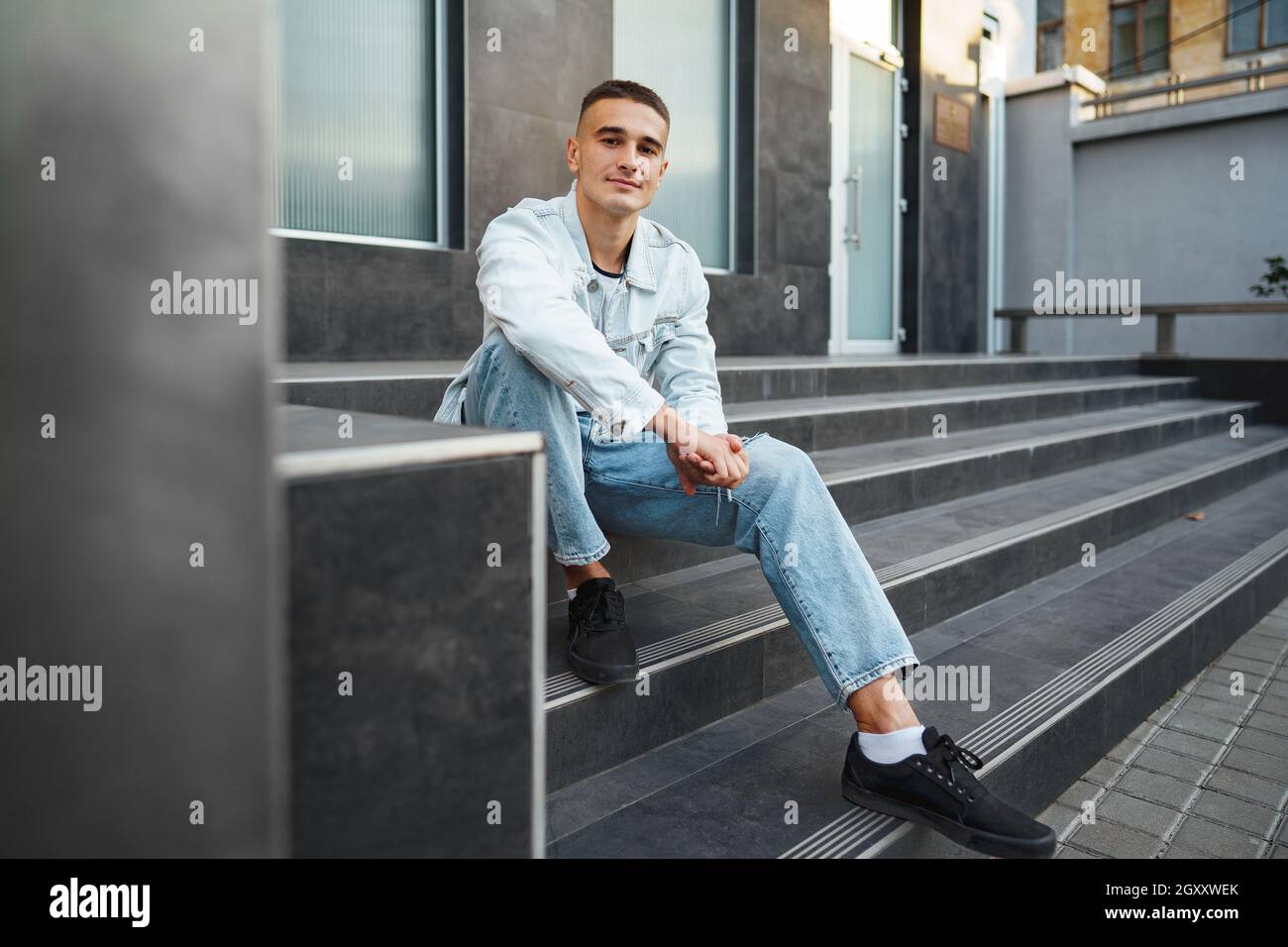 Young casual man sitting on stairs alone on street Stock Photo - Alamy