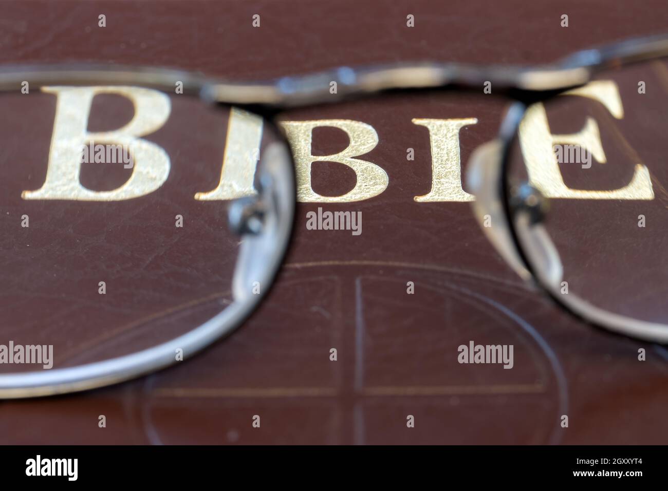 A reading glasses lying on the cover of the Bible, close up. Stock Photo