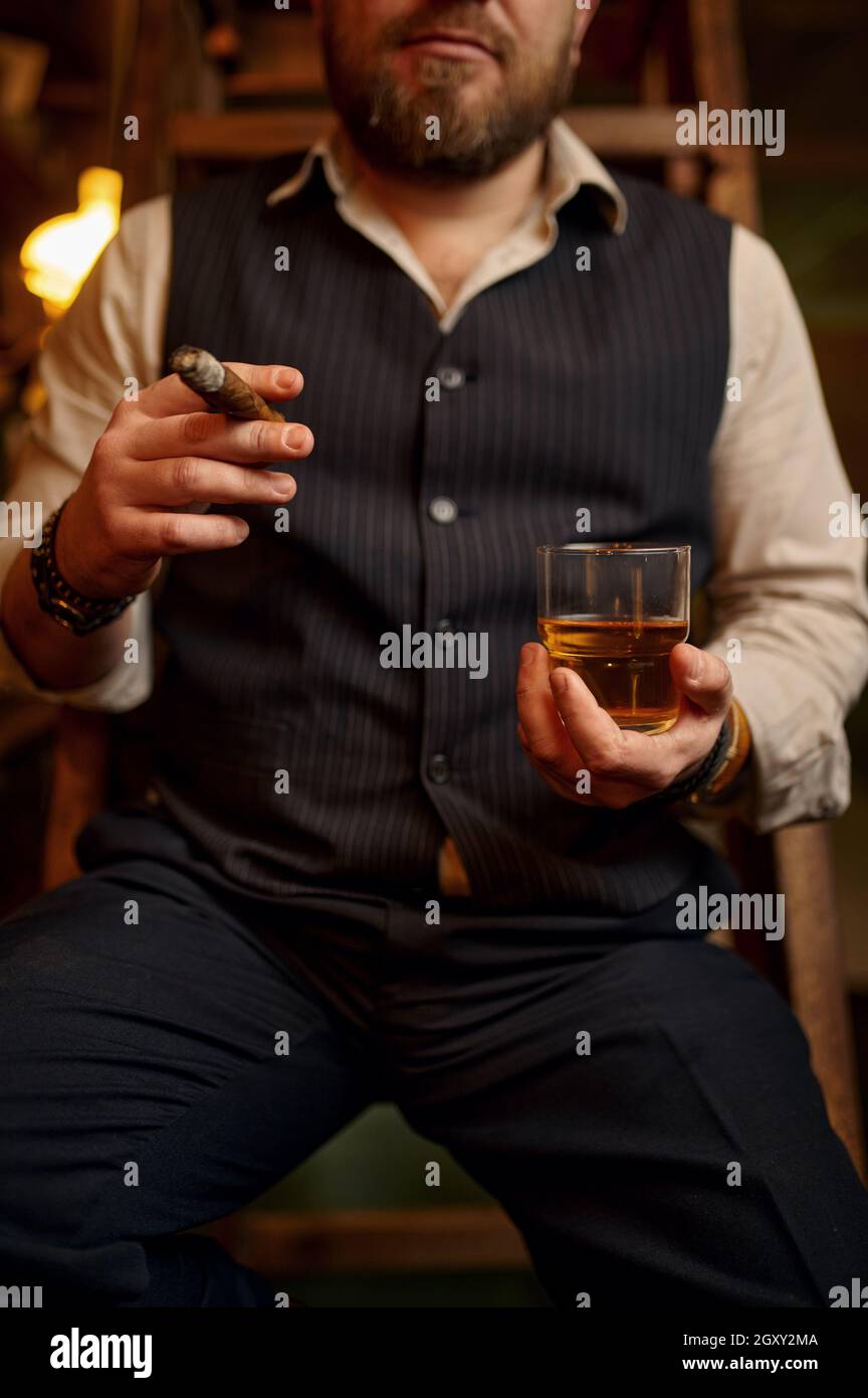 Man smokes a cigar and drinks alcohol beverage, vintage office interior