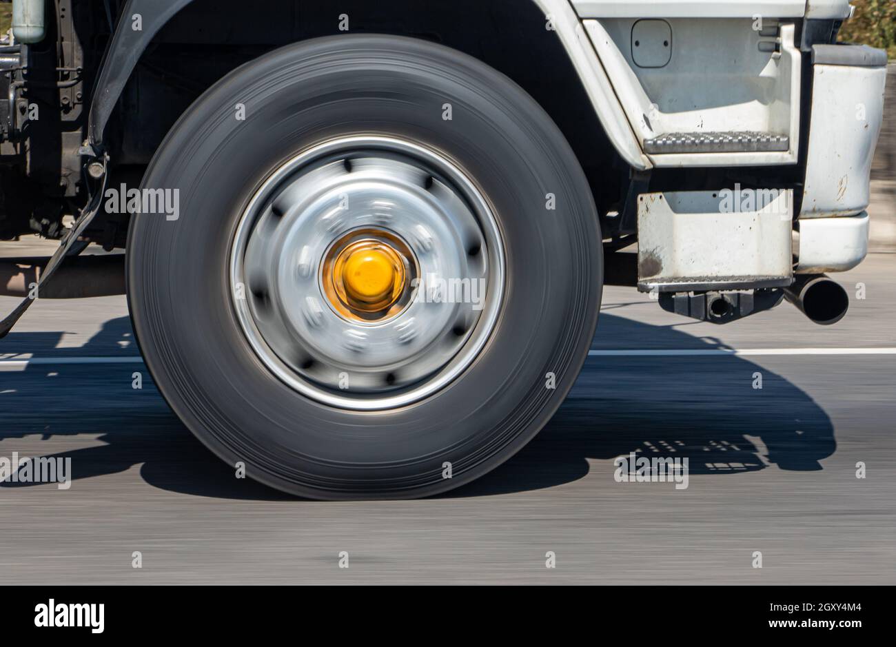 A spinning wheel of a truck running on the road. Detail of a rotating wheel of a truck rides on the highway. Stock Photo