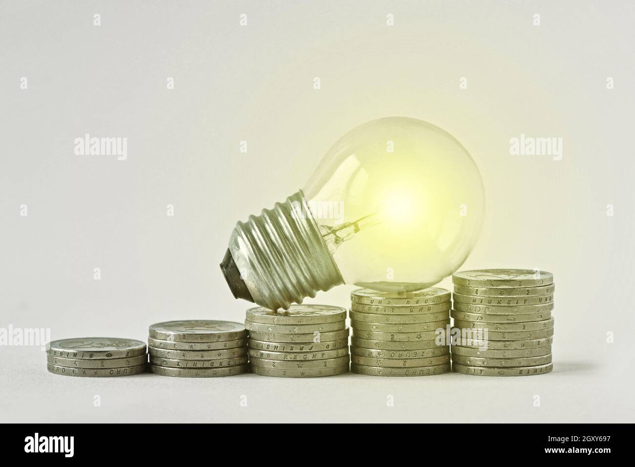 Electric light bulb on raising piles of coins Concept of increase in