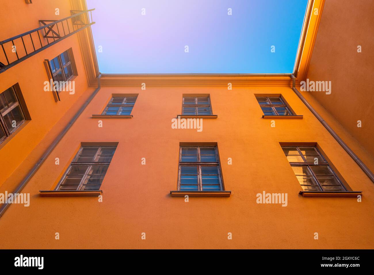 Old orange industrial building with fire escape leading. Low angle view