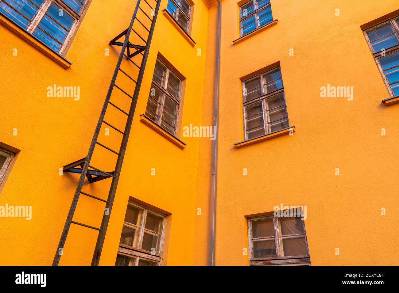 Old orange industrial building with fire escape leading. Low angle view