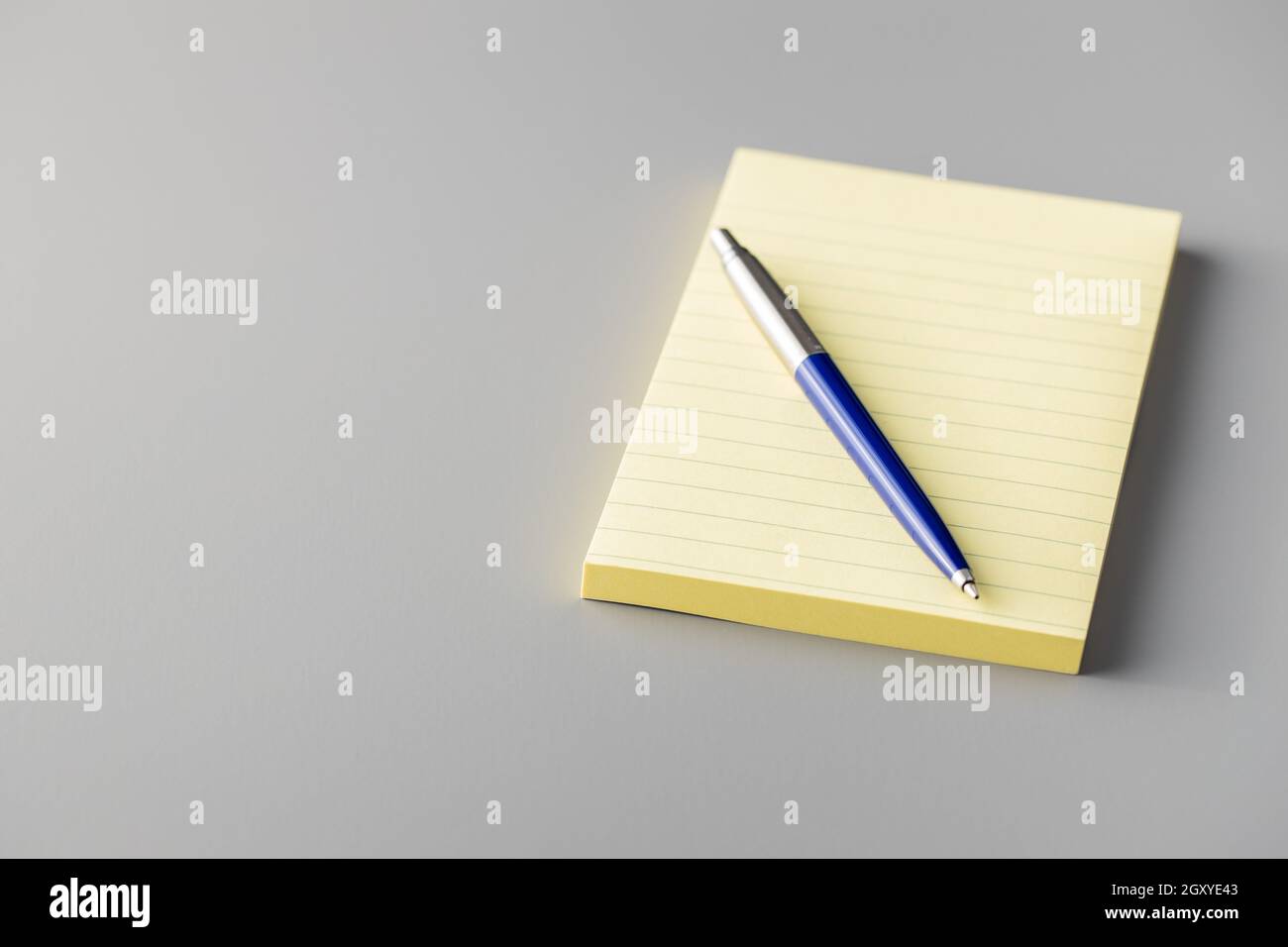 Blank sticky paper notepad and pen on a gray table. Stock Photo