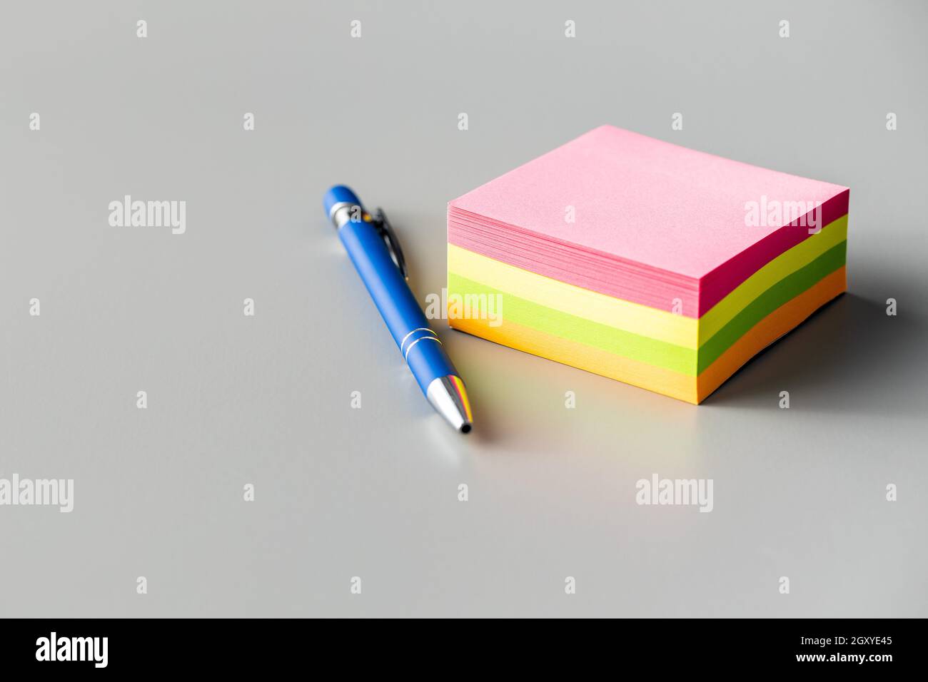 Blank sticky paper notepad and pen on a gray table. Stock Photo