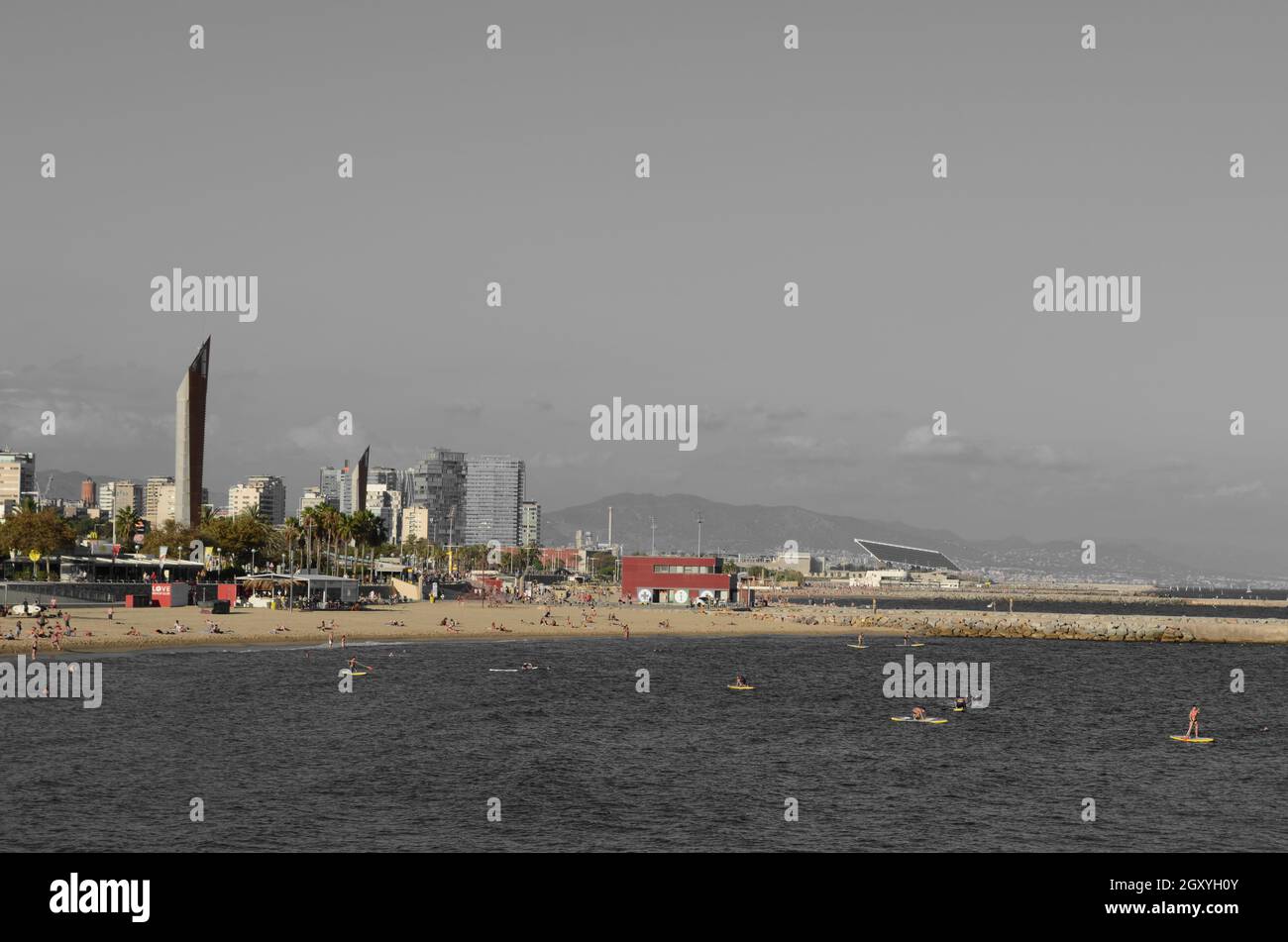 Low color Barcelona beach with people on stand-up paddle boards Stock Photo
