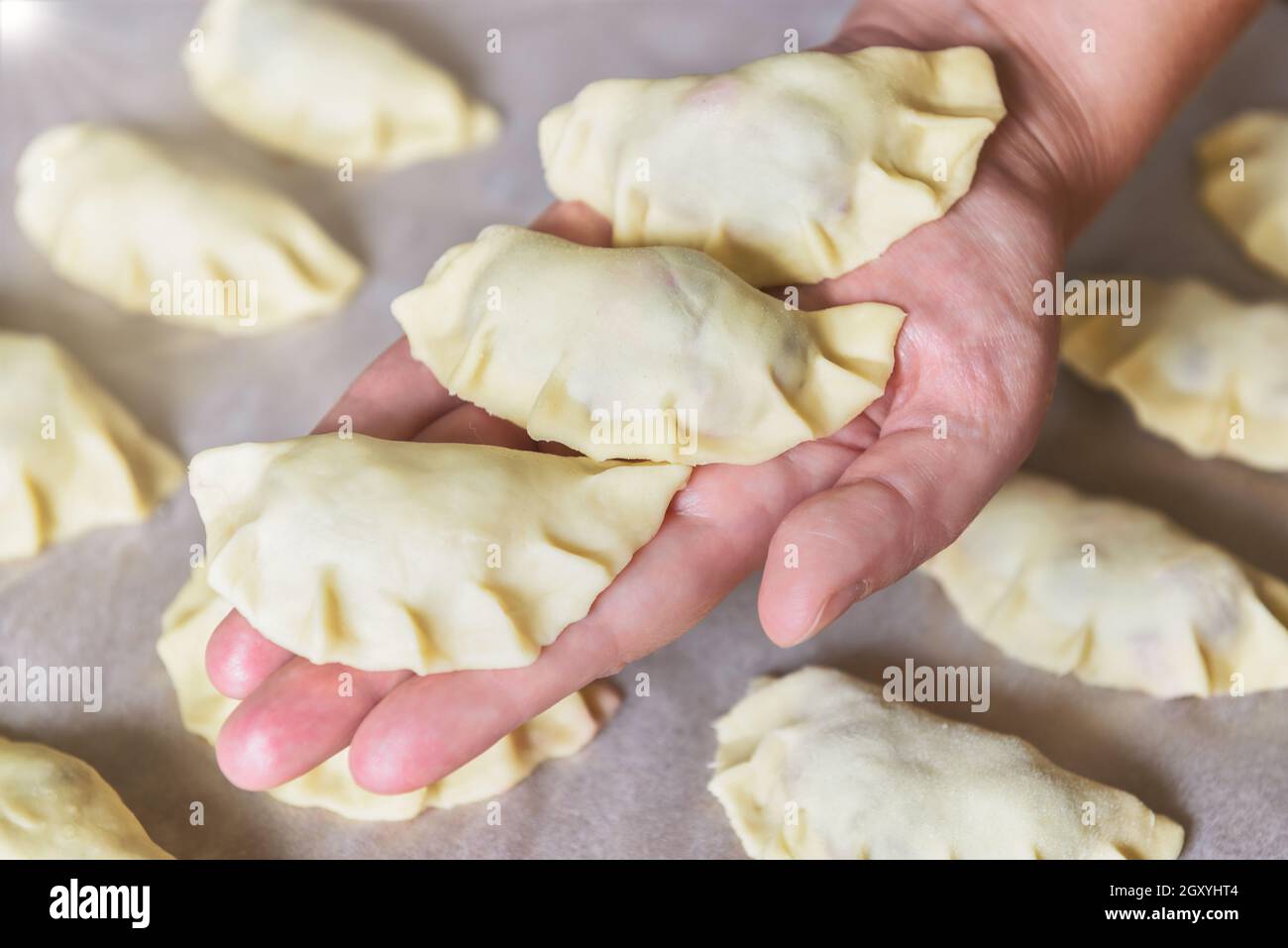 Making dumplings filled with sour cherry with sugar, hand holding freshly made dumplings Stock Photo