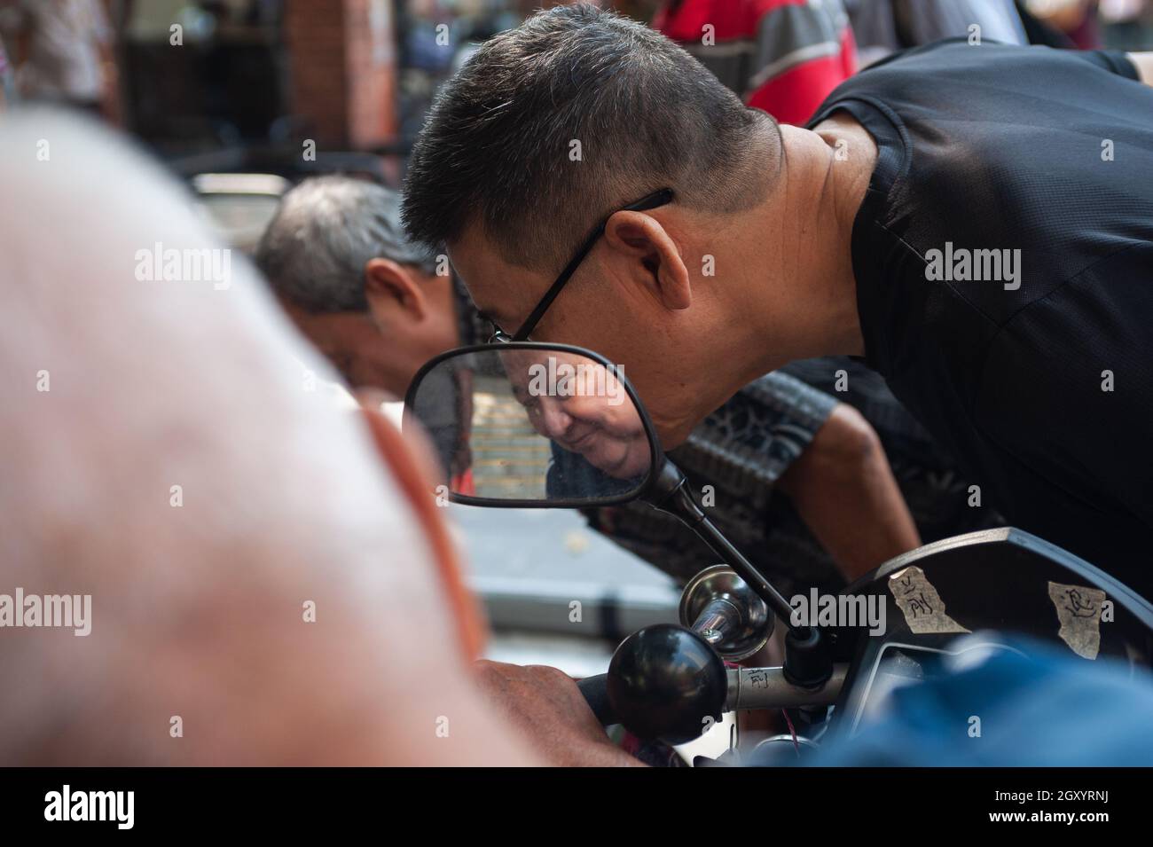04.04.2018, Singapore, Republic of Singapore, Asia - The face of an old man is reflected in a rearview mirror at Kreta Ayer Square in Chinatown. Stock Photo
