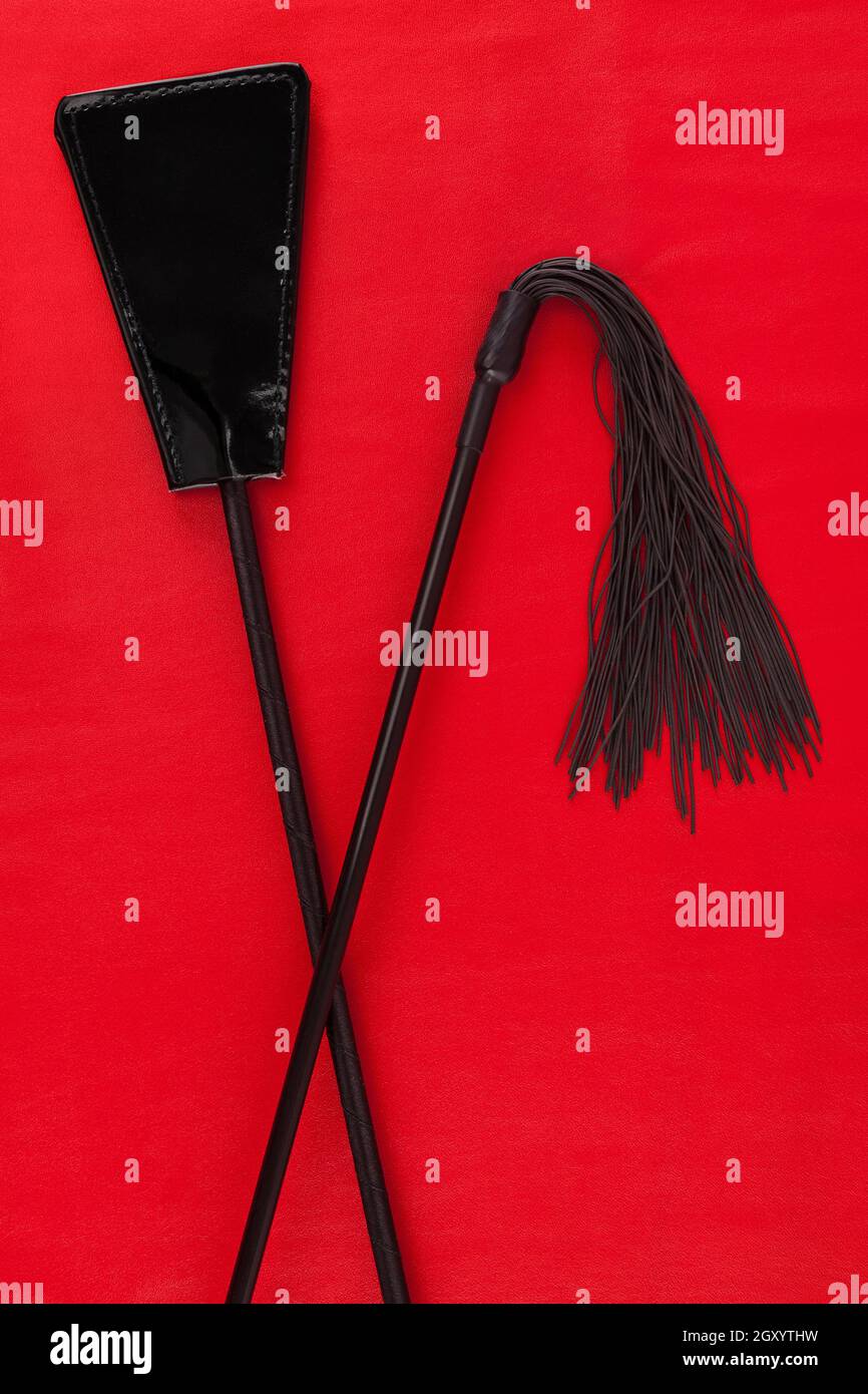 Playful, passionate, romantic, adult bdsm games. Black whips on red background. Stock Photo