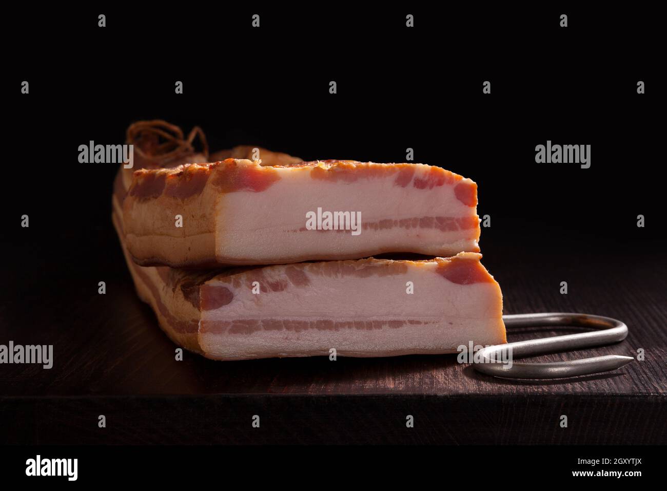 Culinary smoked bacon on dark background. Delicious meat eating. Stock Photo