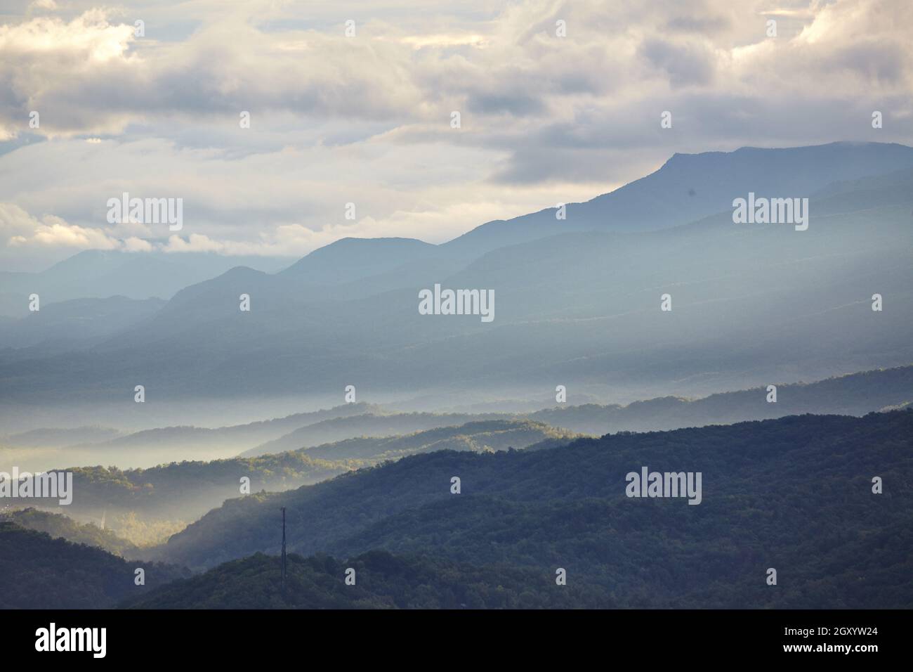 Landscape of the Smokey Mountains with haze between the peaks on an overcast day with one large mountain looming in the background Stock Photo