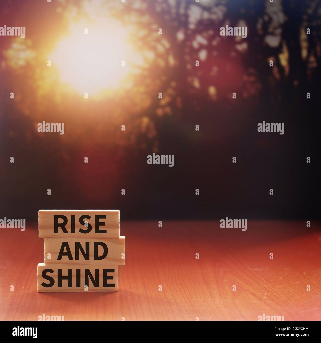 RISE AND SHINE written on wooden tiles with background of bokeh sunrise. Copy space for text Stock Photo