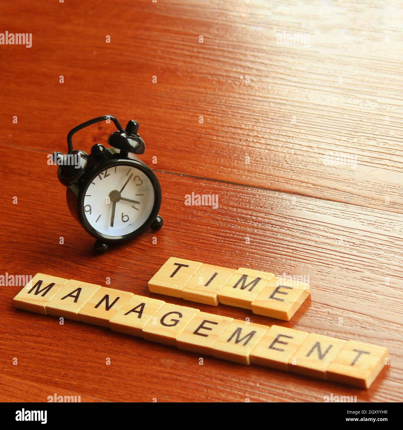 Close up of alarm clock and wooden cube with text TIME MANAGEMENT Stock Photo