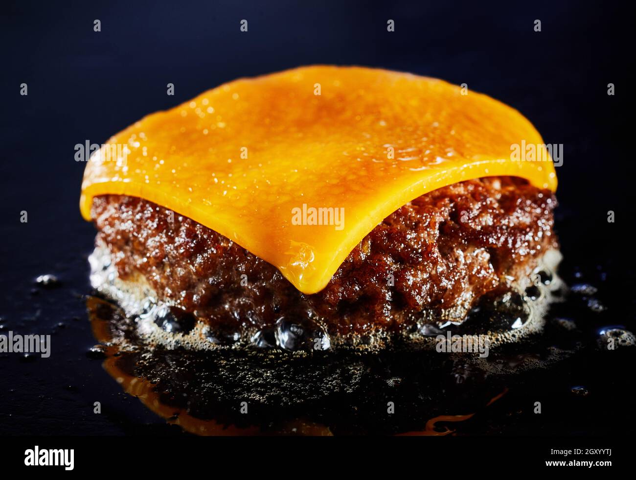 Tasty cheeseburger with beef patty sizzling on a grill in a close up on