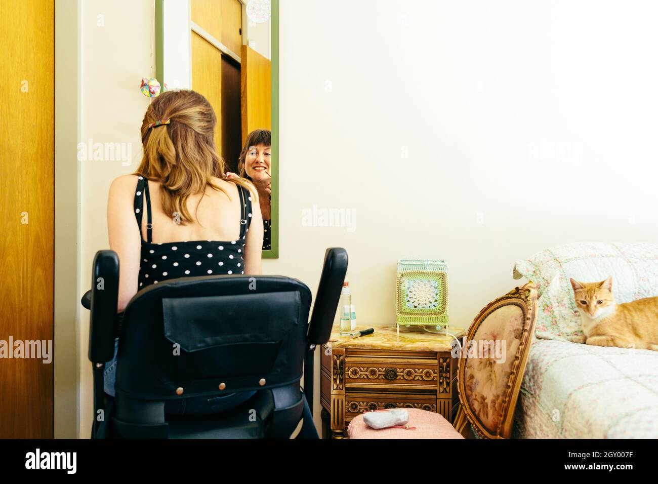 Woman in a wheelchair scooter putting on makeup in front of a mirror. Copy space. Stock Photo